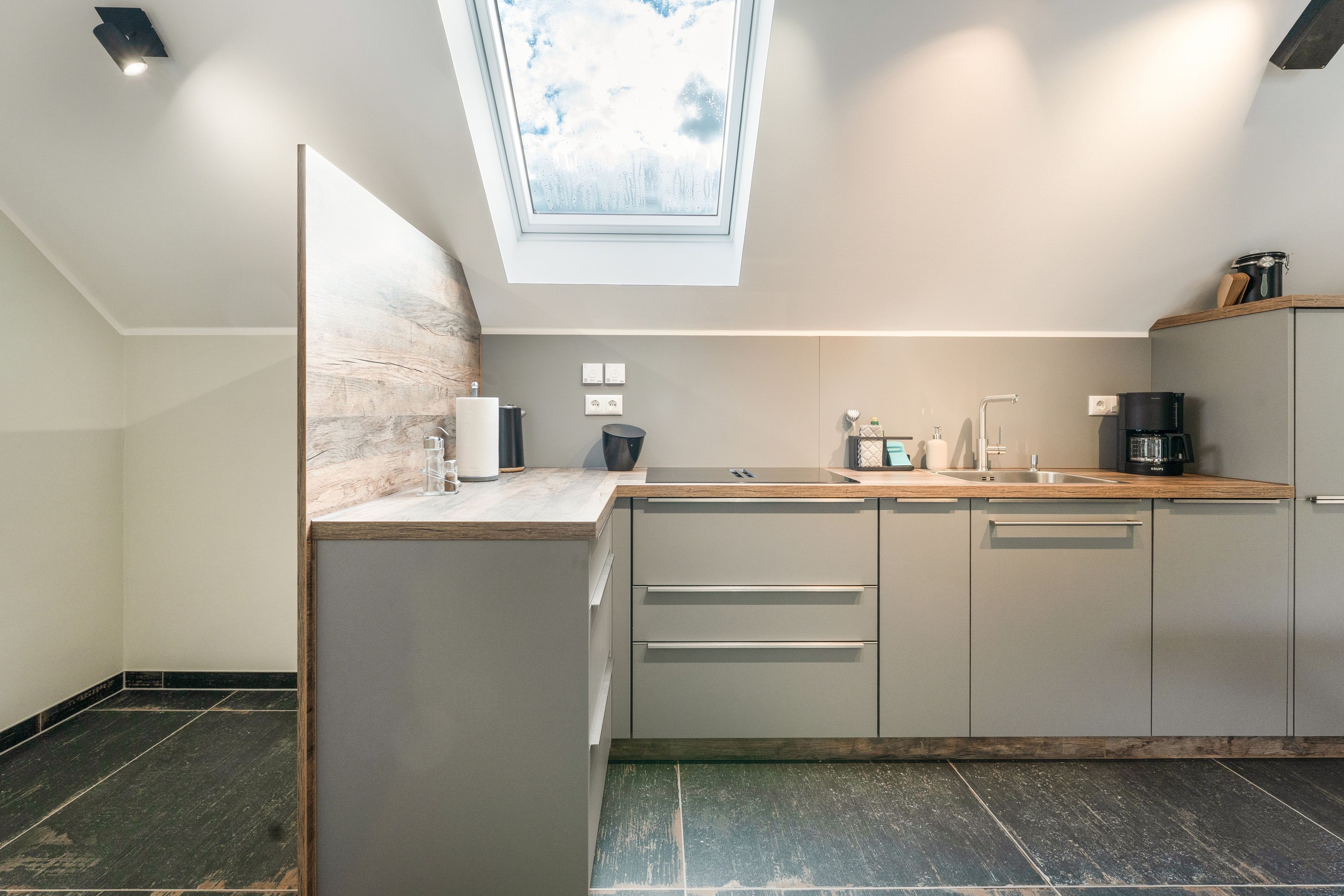 Una cucina moderna con finestra a lucernario, elettrodomestici integrati e un piano di lavoro in legno.