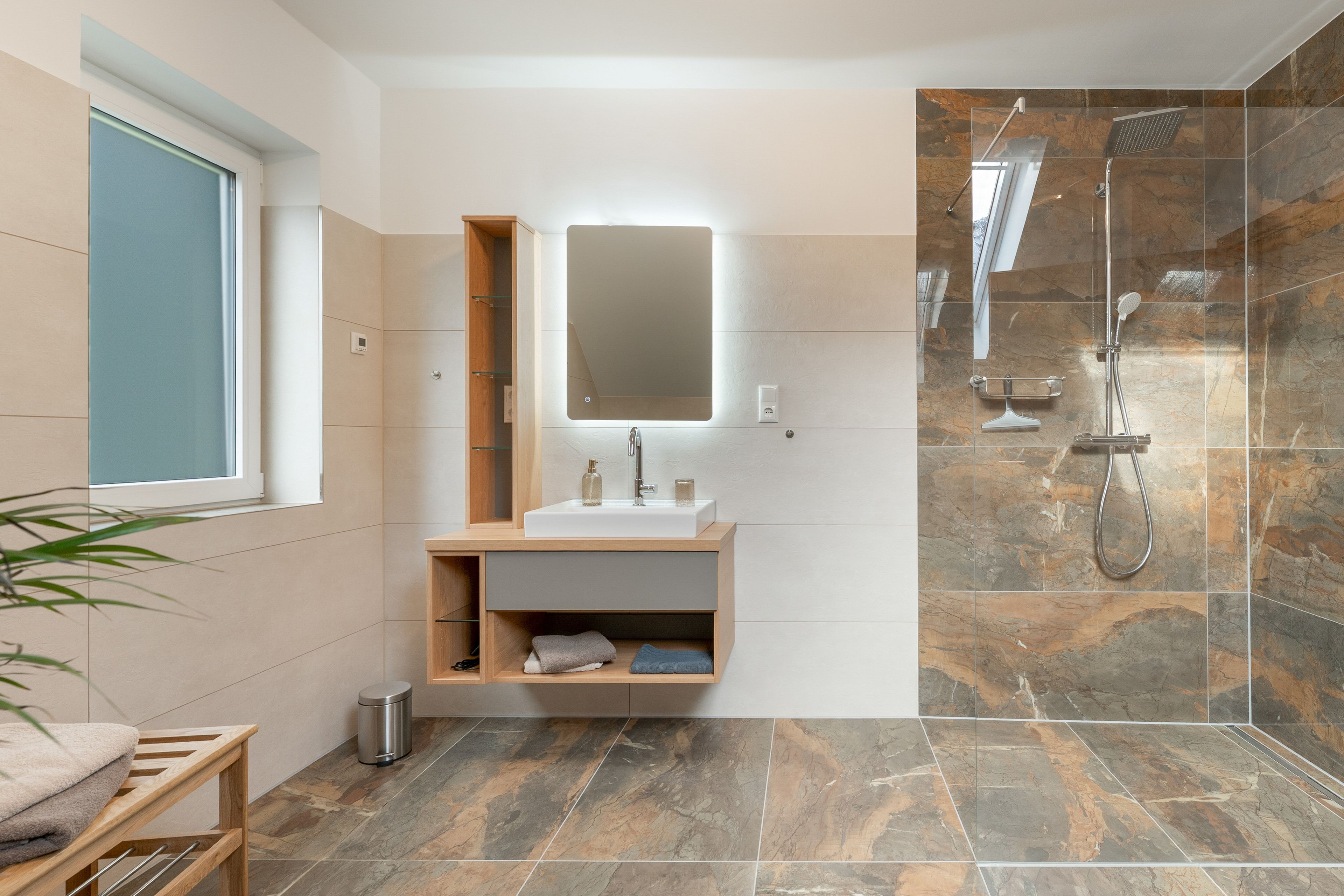 Ein modernes Badezimmer mit einer gläsernen Duschkabine, einem integrierten Waschbecken und einem Spiegel darüber.