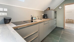 A modern kitchen with a built-in oven, a coffee machine, and a sink.