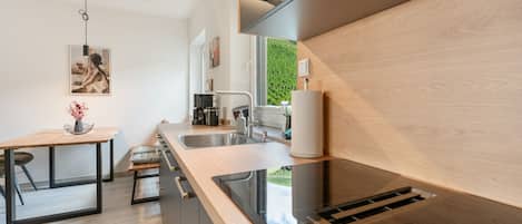 A modern kitchen with a wooden countertop, a sink, and a coffee machine.