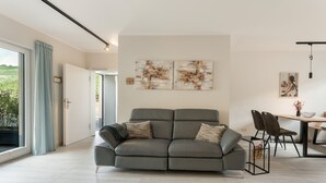 A modern living room with a grey sofa, a dining table with chairs, and artwork on the walls.