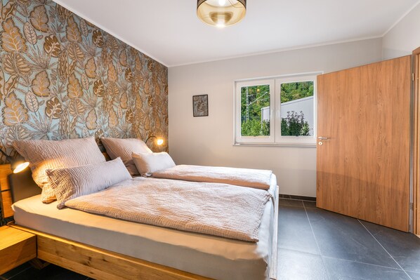 A bedroom with a bed, bedside tables, a window, and a wardrobe.