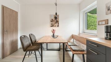Eine moderne Küche mit einem Holztisch, Stühlen, einer Bank und einer Kaffeemaschine.
