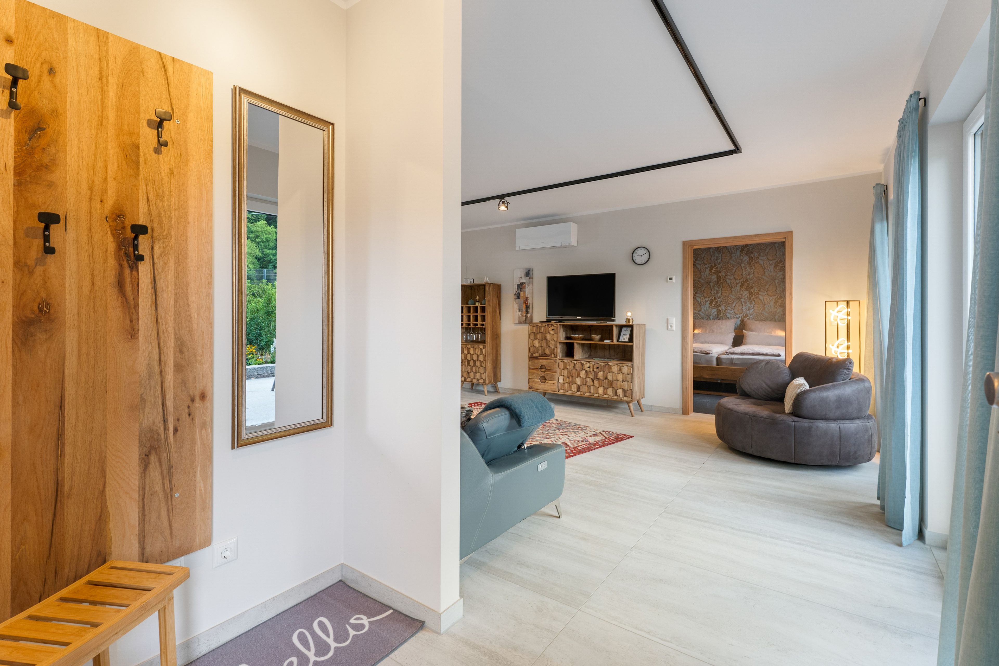 Een moderne woonkamer met een bank, een televisie en een houten kast.