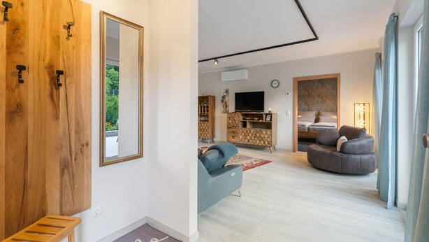 A modern living room with a sofa, a television, and a wooden cabinet.