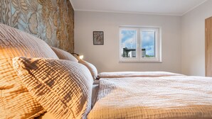 A bedroom with a bed, a window with a view of a building, and a wall with a patterned curtain.