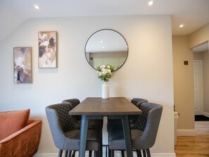 A dining area with a round mirror, two framed artworks, and a vase with flowers on a table. - Town Central Nest - Dingle (Dingle)