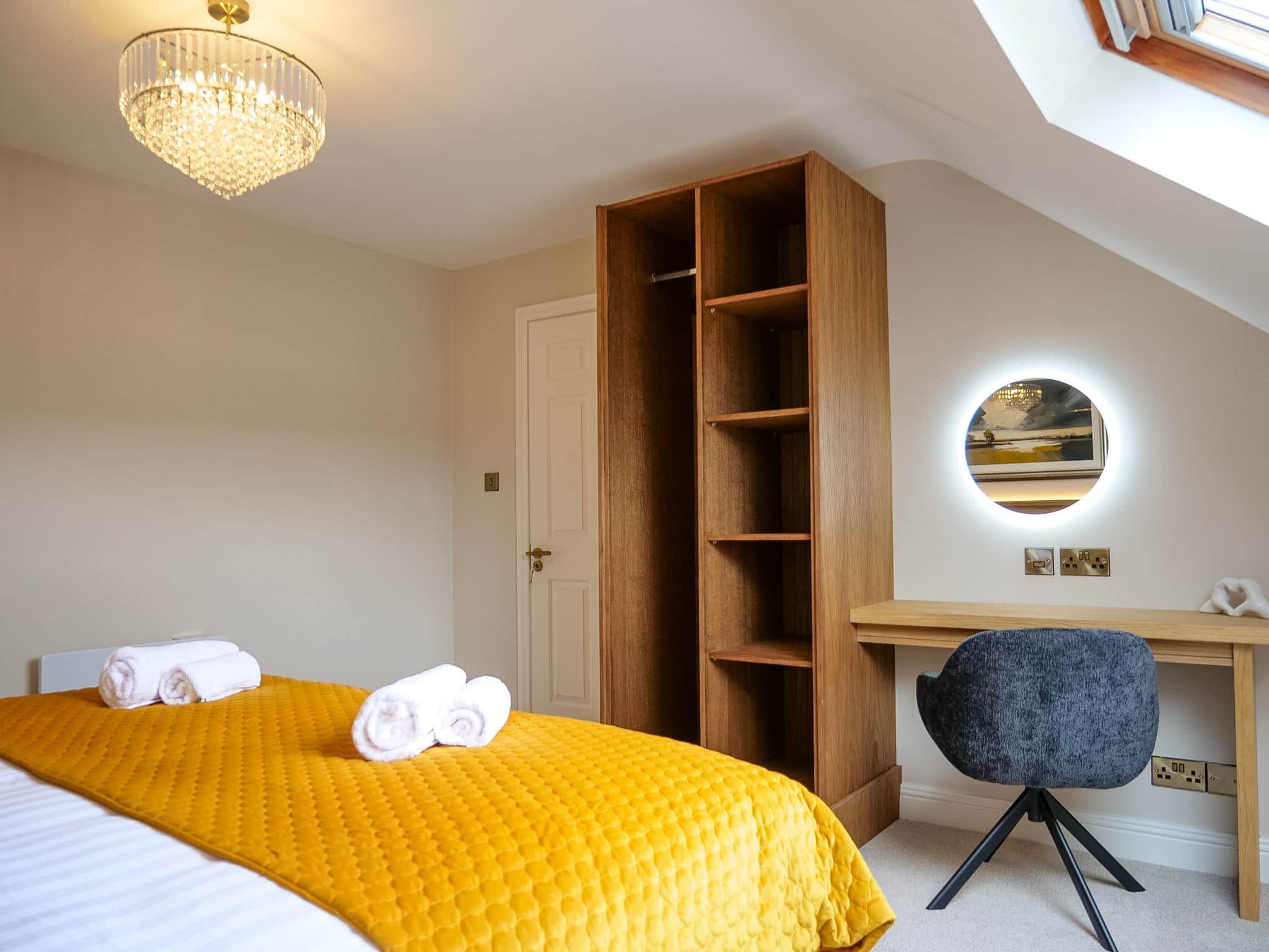 Quarto com cama, escrivaninha, cadeira, guarda-roupa e lustre.