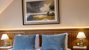 Une chambre d’hôtel avec un lit, un tableau, deux lampes de chevet et un lustre.