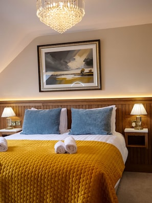 A hotel room with a bed, a painting, two bedside lamps, and a chandelier. - Town Central Nest - Dingle (Dingle)