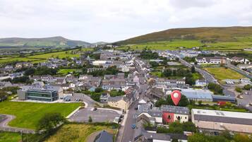 A town with a mix of residential and commercial buildings, a main road, and surrounding green fields.