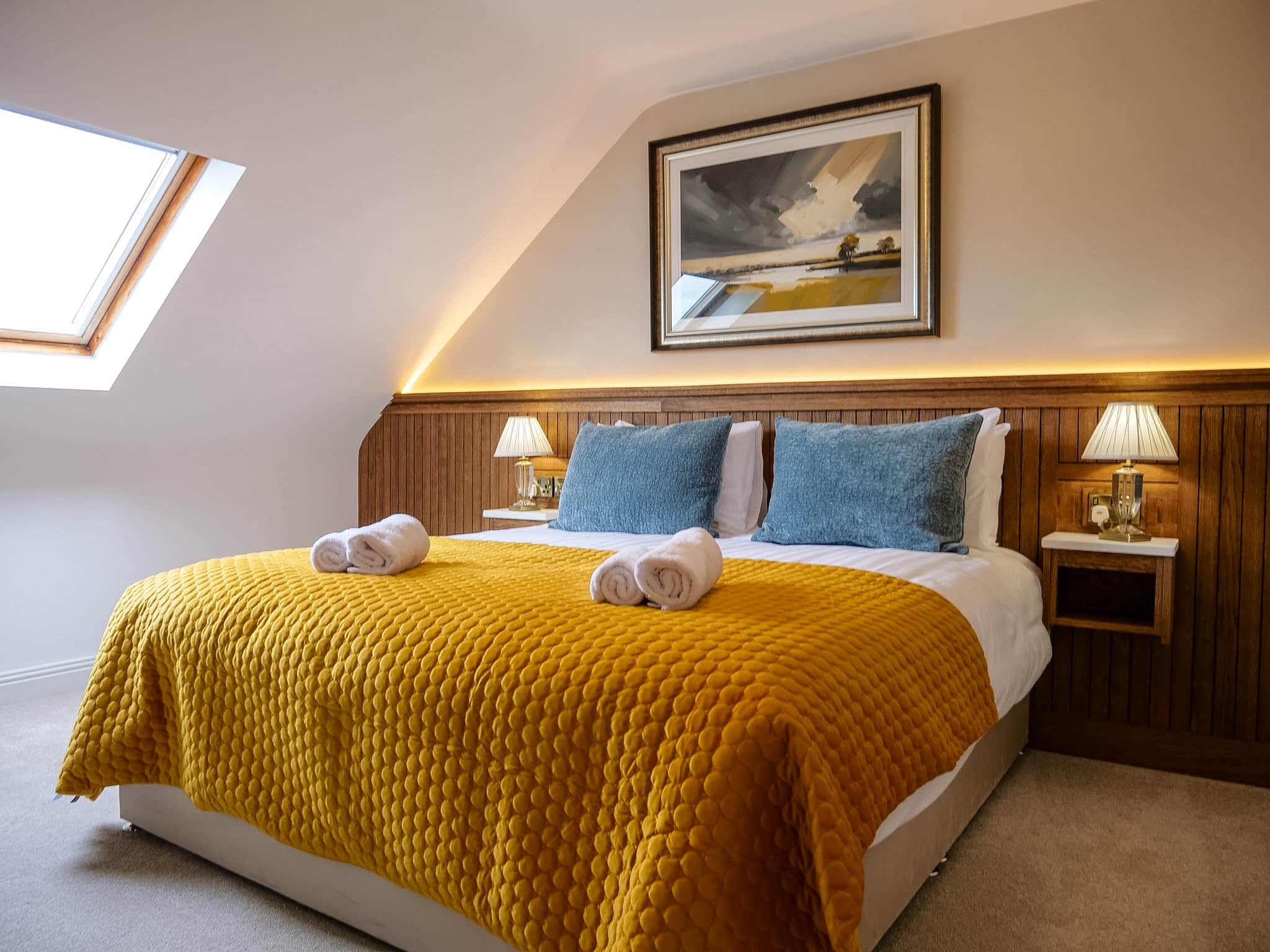 Ein Hotelzimmer mit einem Bett, zwei Nachttischen, einem Bild an der Wand und einem Oberlicht.
