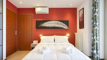 Ein Hotelzimmer mit einem Bett, einer Wand-Klimaanlage, einer gerahmten Feder-Kunstarbeit, einem gerahmten Bild und einem Vorhang mit Blätermuster.