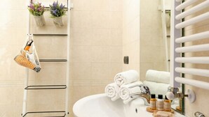 A bathroom with a white sink, a towel rack with folded towels, a hanging net, and a mirror with a towel rack.