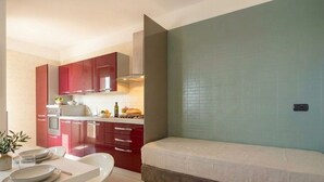 A compact kitchen with red cabinets, a white countertop, and a small dining table.