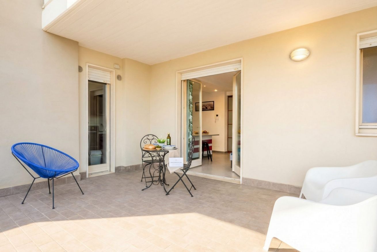 Ein kleiner Patio-Bereich mit Tisch und Stühlen, ein blauer Stuhl und ein weißer Stuhl.