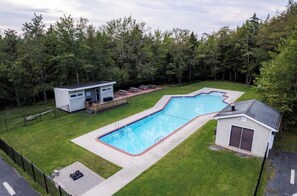 Ein Wohngebiet-Schwimmbecken mit einer Poolterrasse, einer kleinen Gartenhütte und einem eingezäunten Garten.