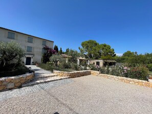 Une cour avec un chemin de gravier menant à un bâtiment doté d’une porte bleue.