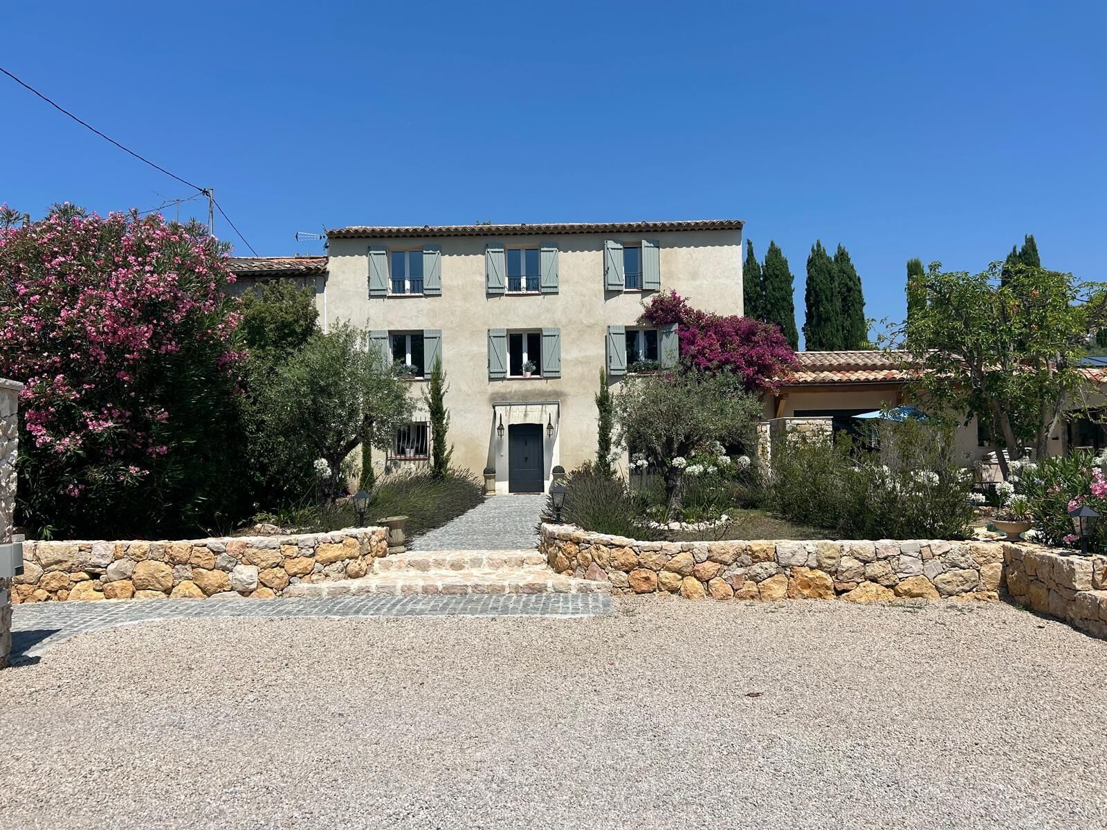 A two-story building with a stone facade, a central entrance, and a paved driveway leading to the entrance.