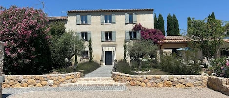 A two-story building with a stone facade, a central entrance, and a paved driveway leading to the entrance.