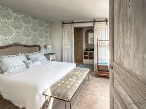 Ein Schlafzimmer mit Bett, Nachttisch, Lampe und einer Bank.