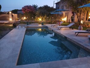 Une piscine avec des chaises longues et un mur en pierre.