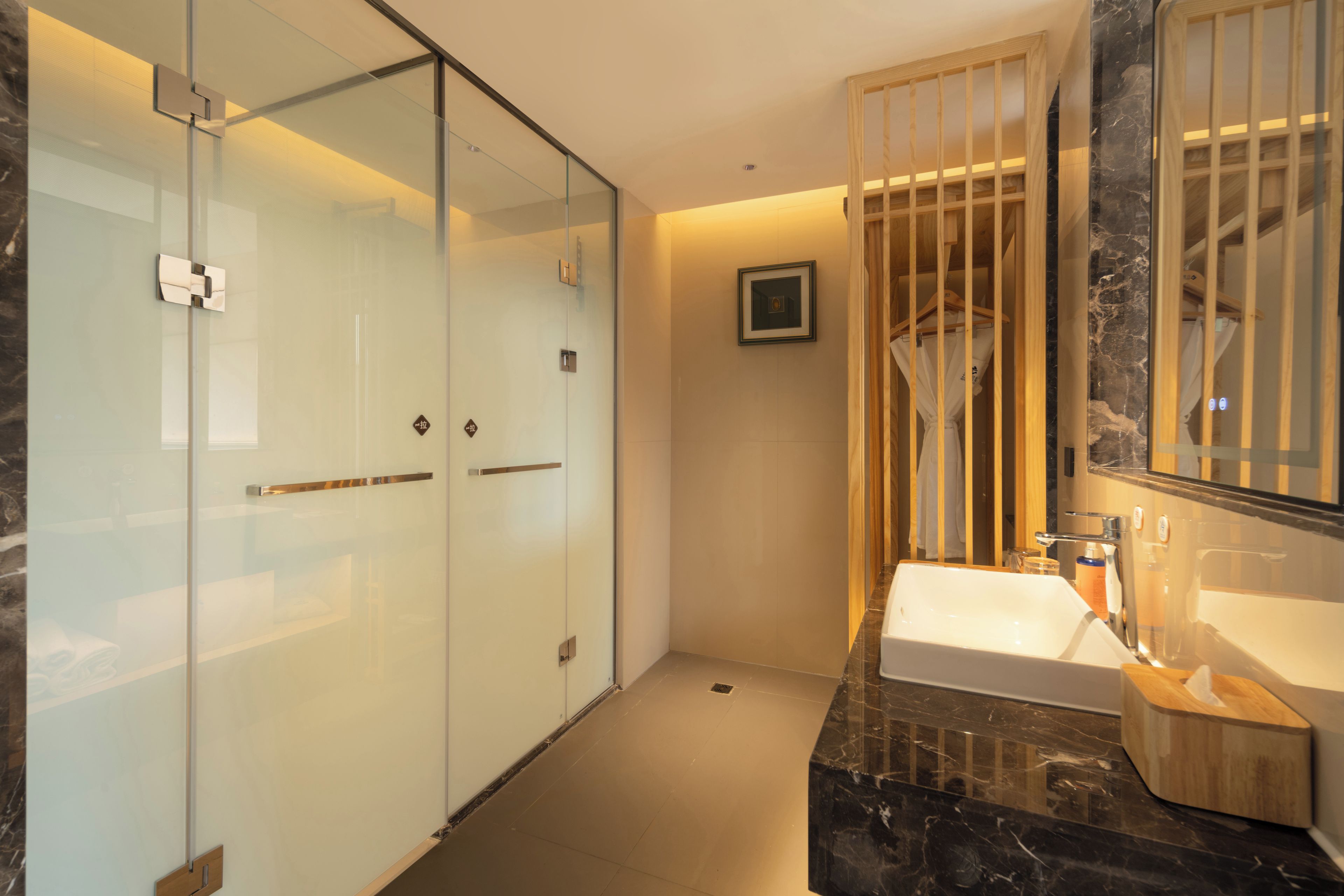 Ein modernes Badezimmer mit einer Duschkabine aus Glas, einem Marmorwaschbecken und einem Holzbadezimmermöbel.