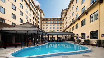A hotel courtyard with a swimming pool, covered seating area, and multiple hotel buildings.