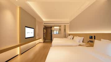 A hotel room with a large bed, a smaller bed, a desk with a lamp, and a television on the wall.