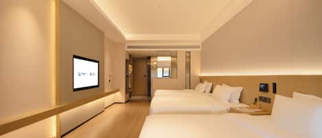 A hotel room with a large bed, a smaller bed, a desk with a lamp, and a television on the wall.