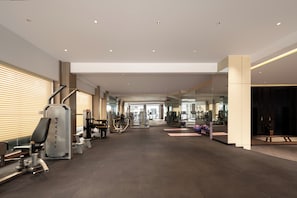 A spacious gym with various exercise equipment, a mirrored wall, and a modern design.
