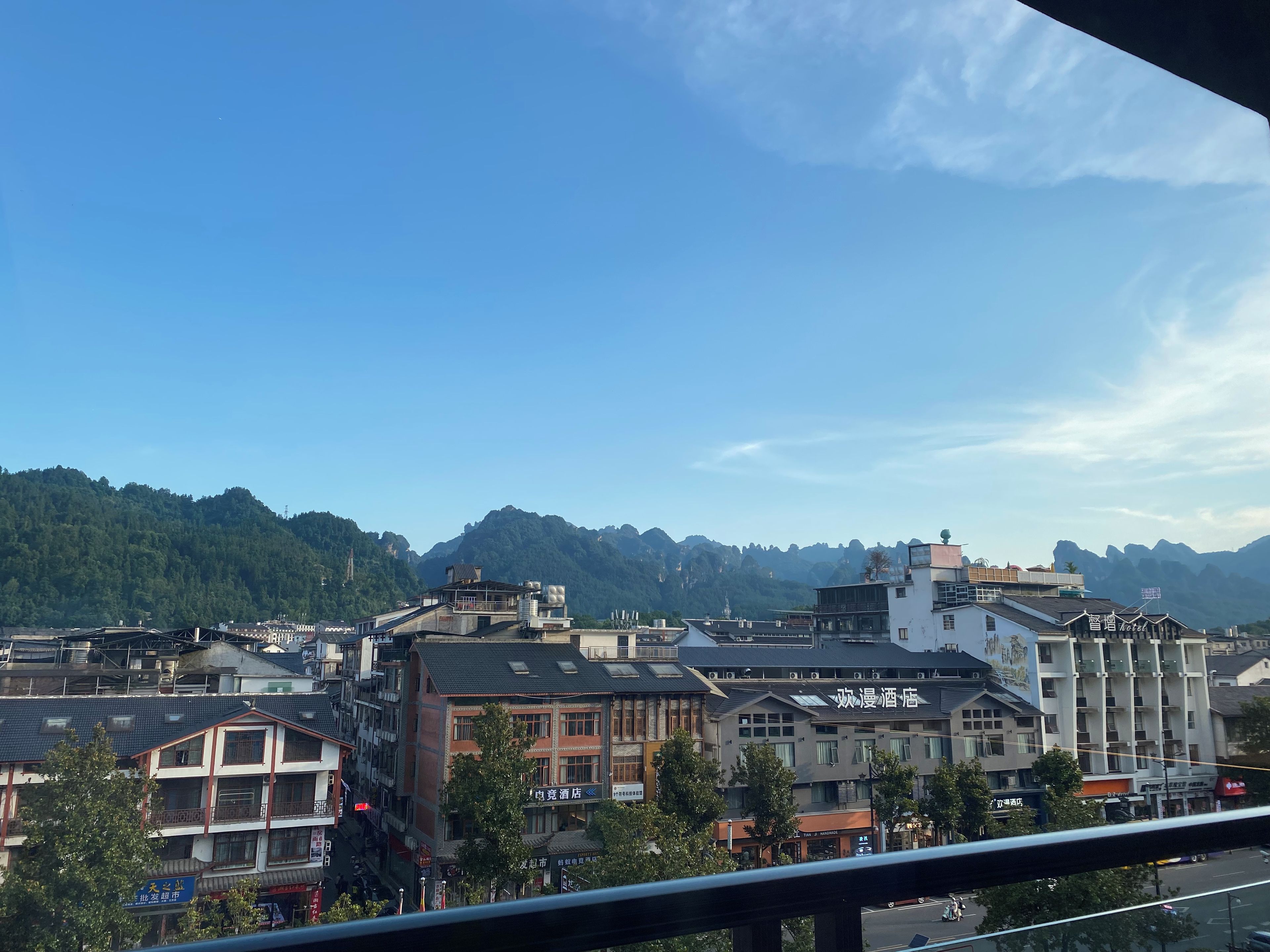 Un hotel con varios pisos, un balcón y vistas de la ciudad y las montañas circundantes.