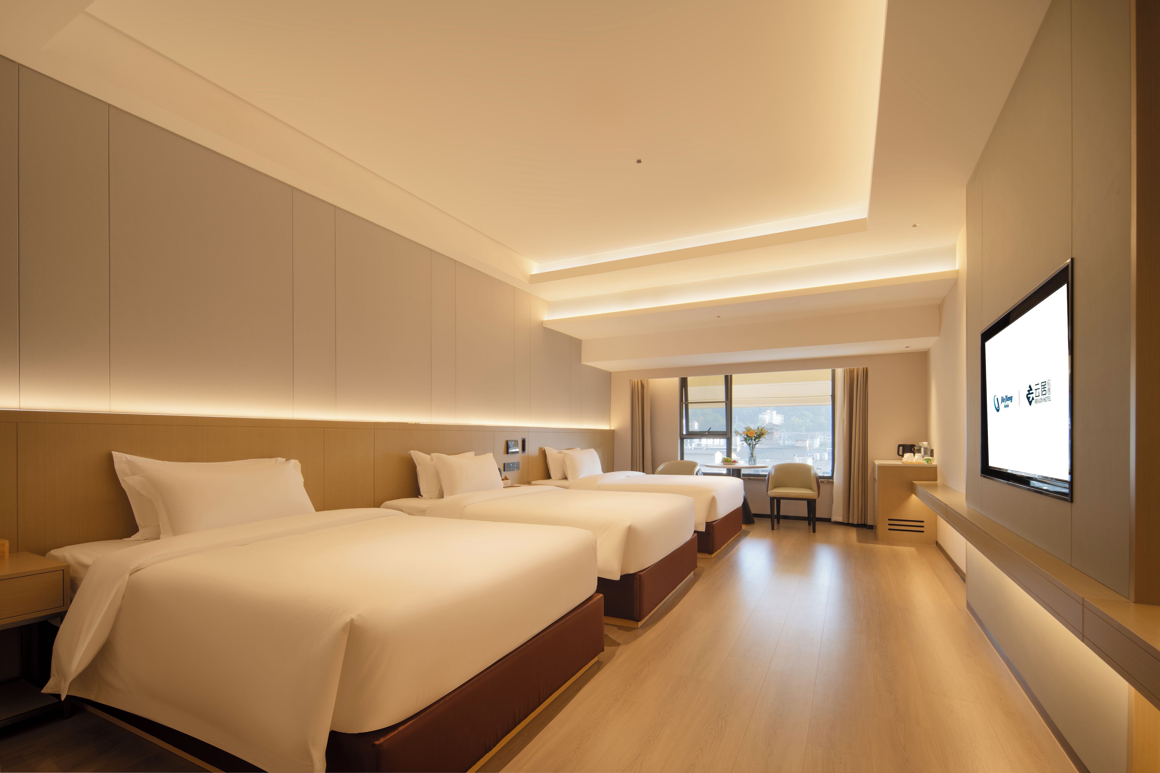 A hotel room with two beds, a desk, and a large window.