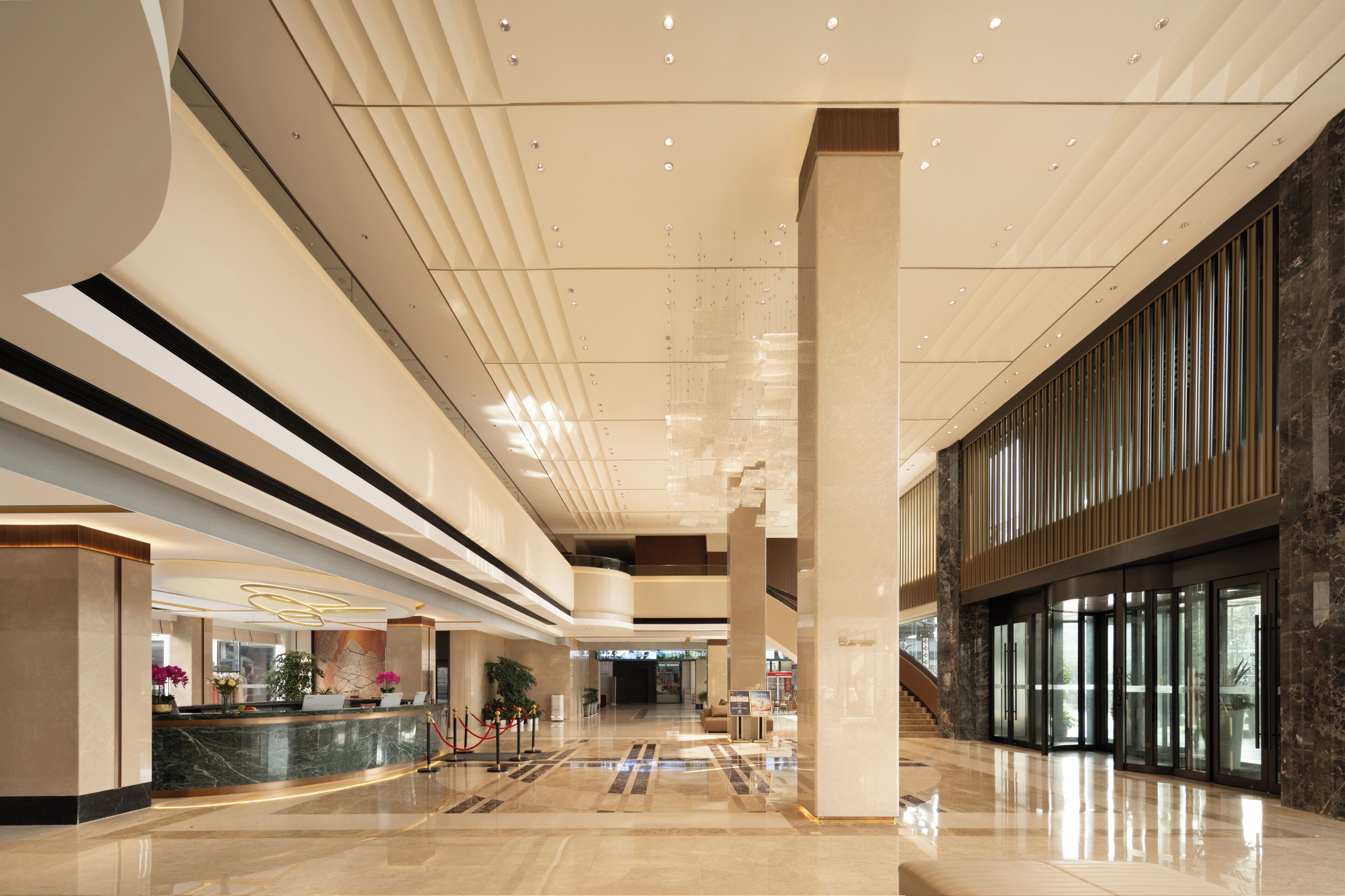 A spacious lobby with a high ceiling, marble flooring, and a reception desk.