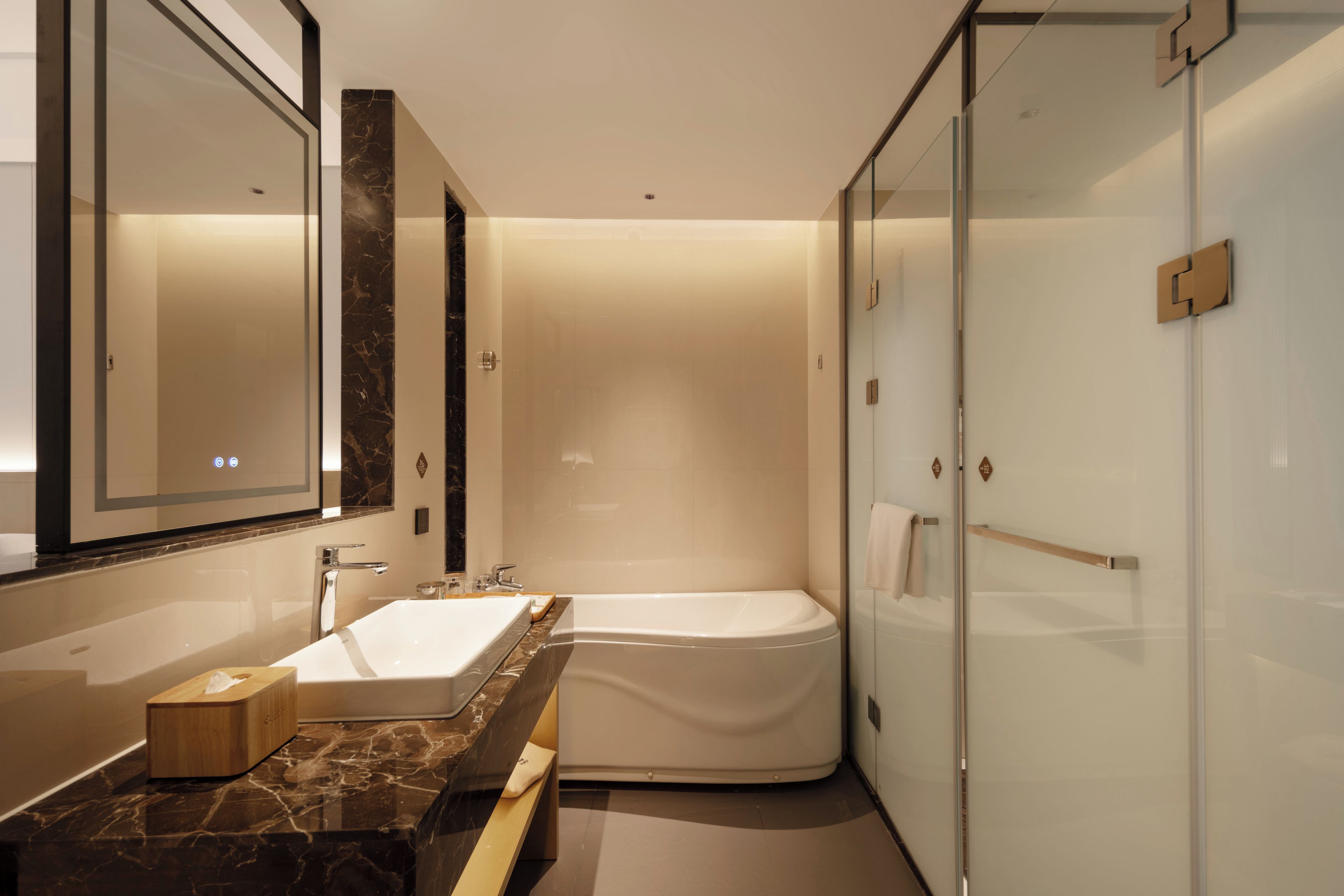 Ein modernes Badezimmer mit Marmorwaschtisch, einer Badewanne und einer Duschkabine aus Glas.