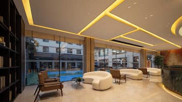 A modern lobby with a seating area, a reception desk, and a view of the outside.