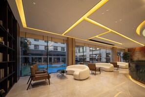 A modern lobby with a seating area, a reception desk, and a view of the outside.
