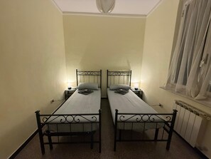 Ein Zimmer mit zwei gleich aussehenden Betten, jeweils mit einem Nachttisch und einer Lampe.
