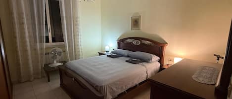 A bedroom with a bed, bedside table, lamp, and a ceiling fan.
