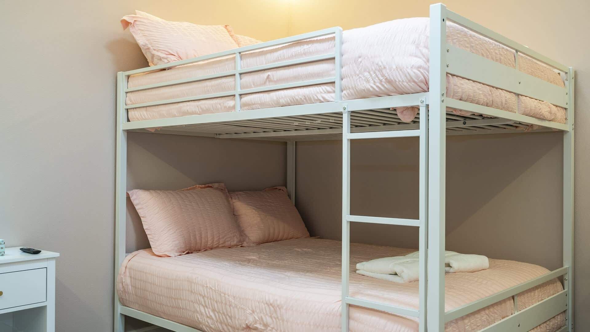 Un lit superposé à deux niveaux, chaque niveau étant équipé d’oreillers et d’une couverture.