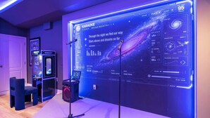 Ett karaoke-system med en digital display, ett mikrofonstativ och en spelmaskin.