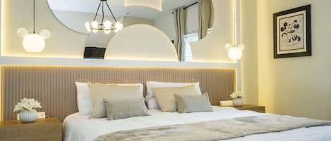 Habitación de hotel con una cama grande, cabecera con iluminación integrada, un cuadro enmarcado de Mickey Mouse y un diseño de techo único.