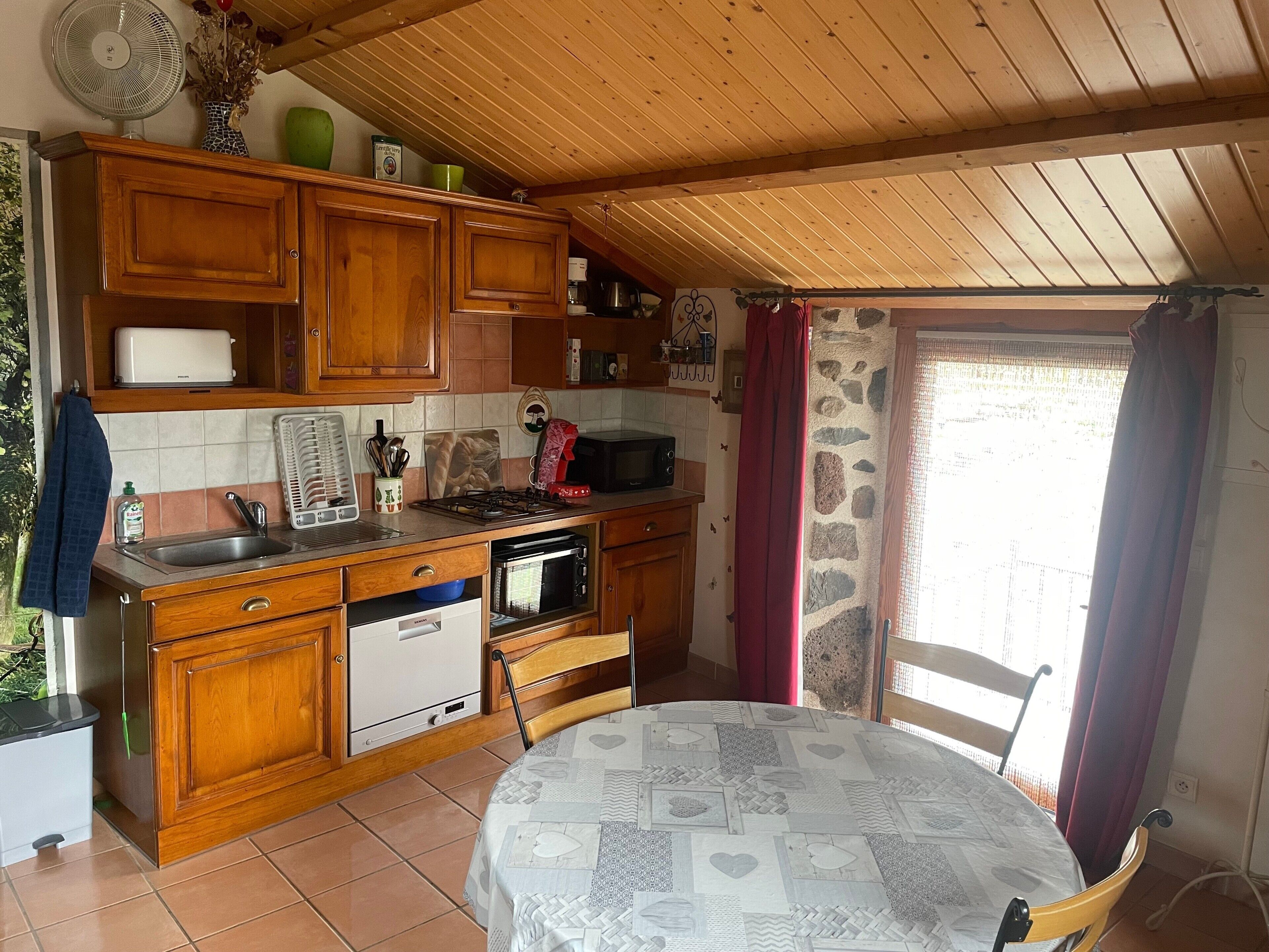 A compact kitchen with wooden cabinets, a gas stove, a microwave, and a sink.