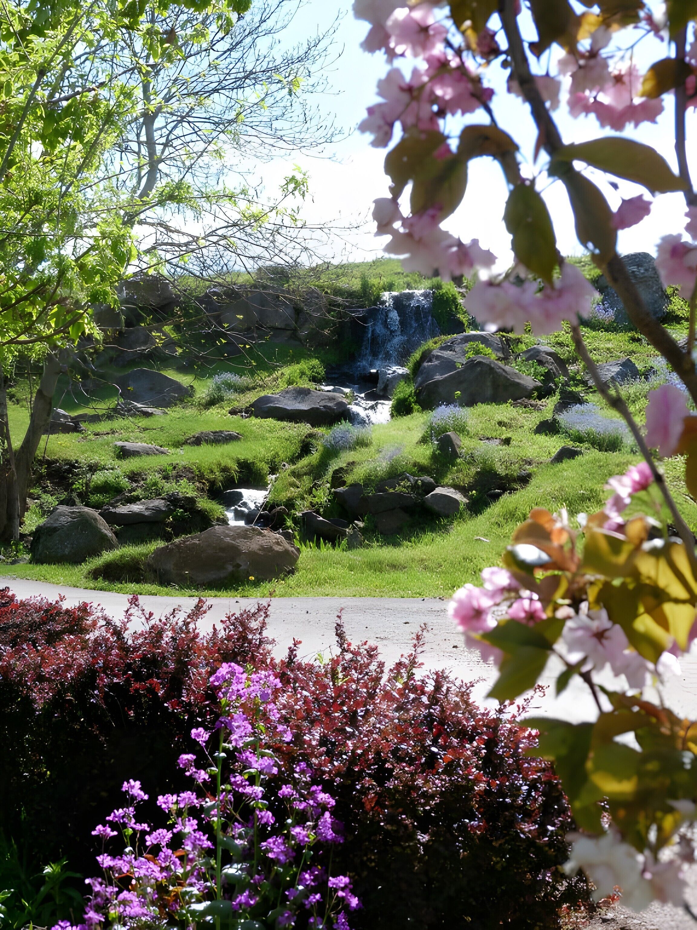 A natural landscape with a waterfall, rocks, and greenery.