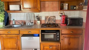 A kitchen with wooden cabinets, a Siemens dishwasher, a black oven, a microwave, and a gas stove.