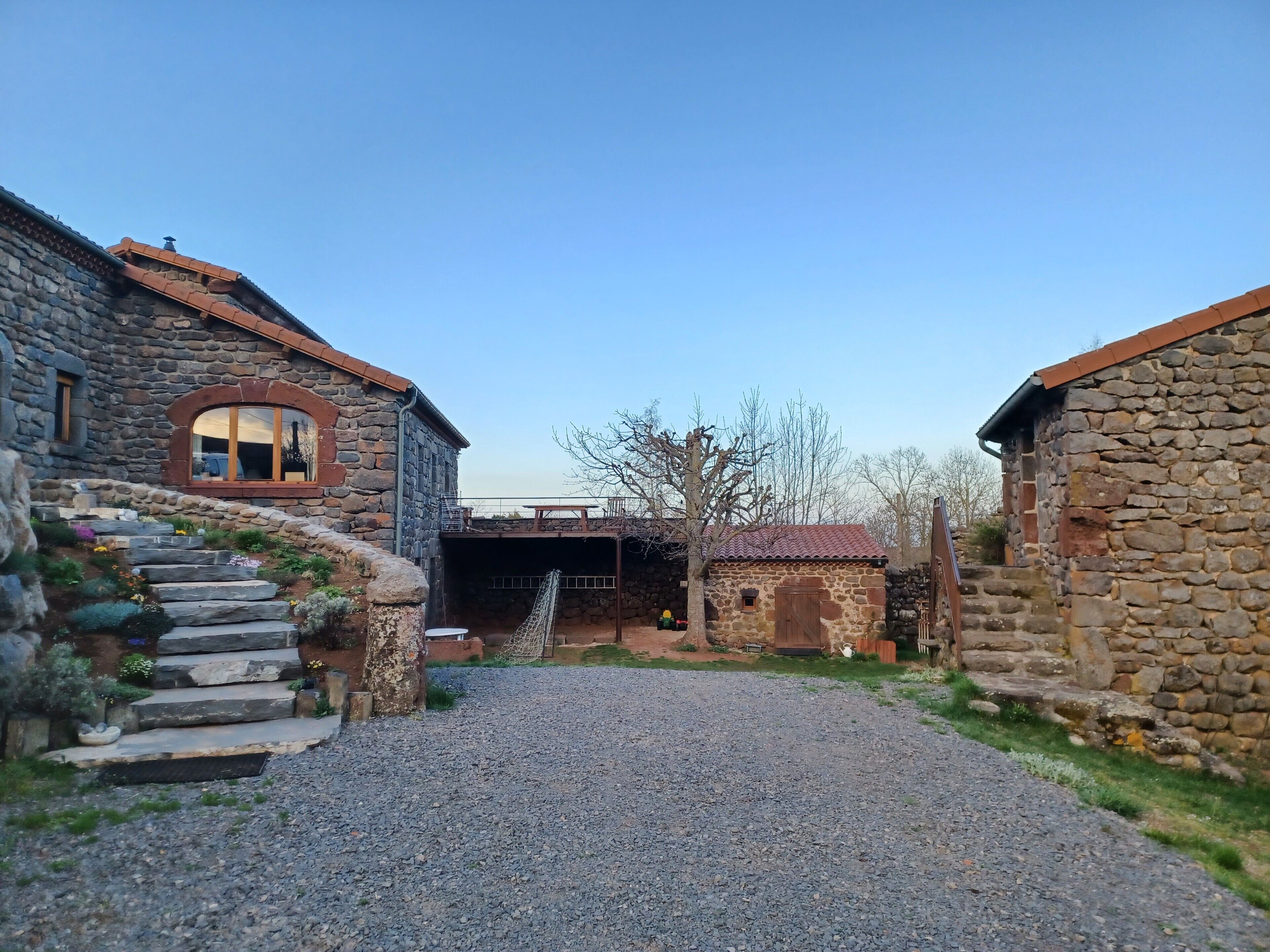 A stone building with a gravel driveway leading to a covered entrance.