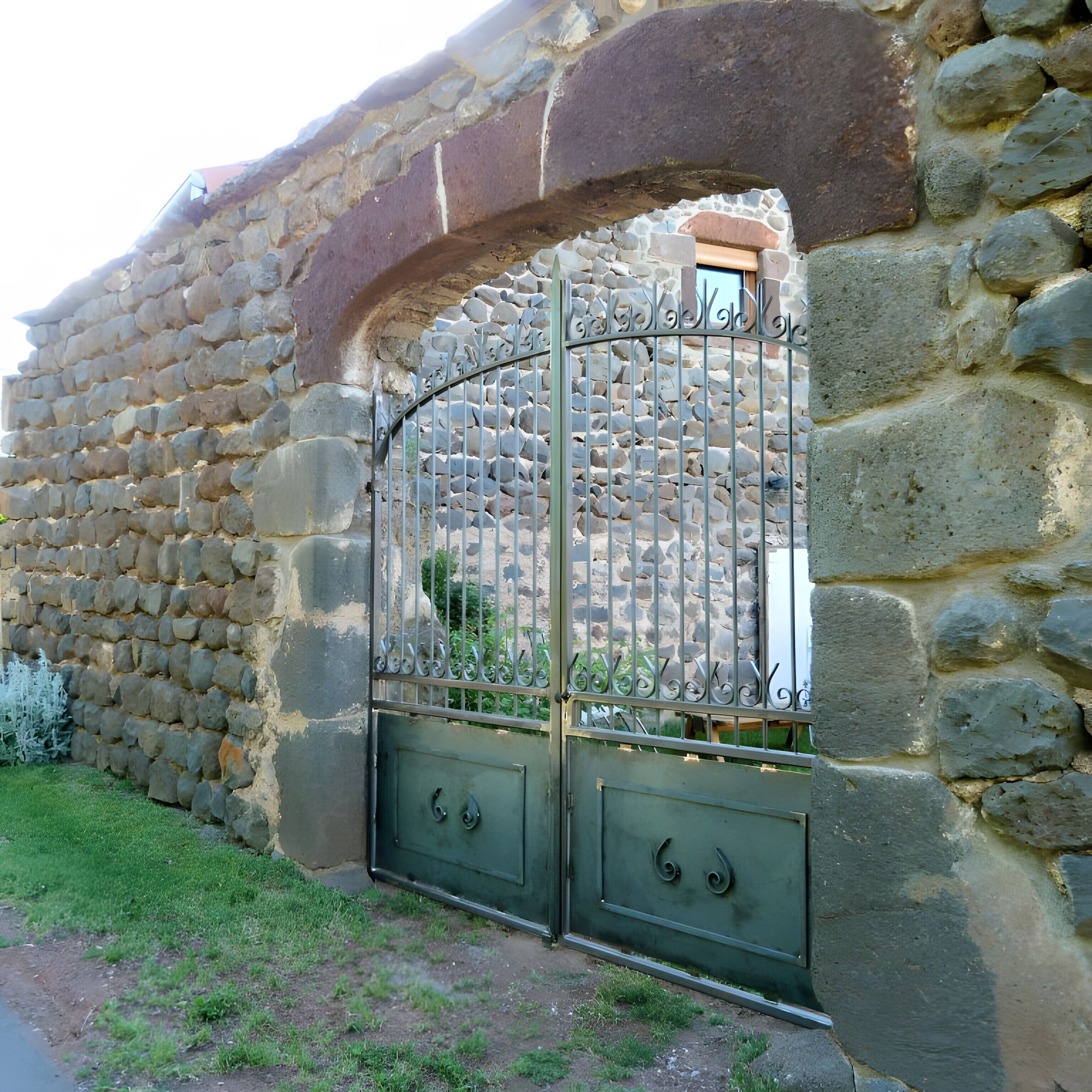 Un muro de piedra con una reja metálica.