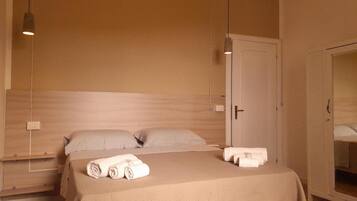 Une chambre d’hôtel avec un lit, deux oreillers, une table de chevet, un miroir et une porte.