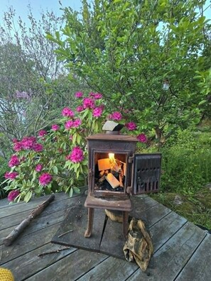 A wood-burning stove on a wooden deck with a flower bush in the background. - Cottage gem with views of the Oslo Fjord (Akershus)