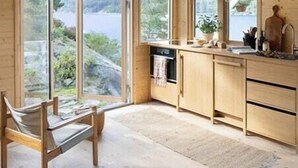 A wooden interior with a kitchen, a dining area, and large windows offering a view of the outdoors. - Cottage gem with views of the Oslo Fjord (Akershus)